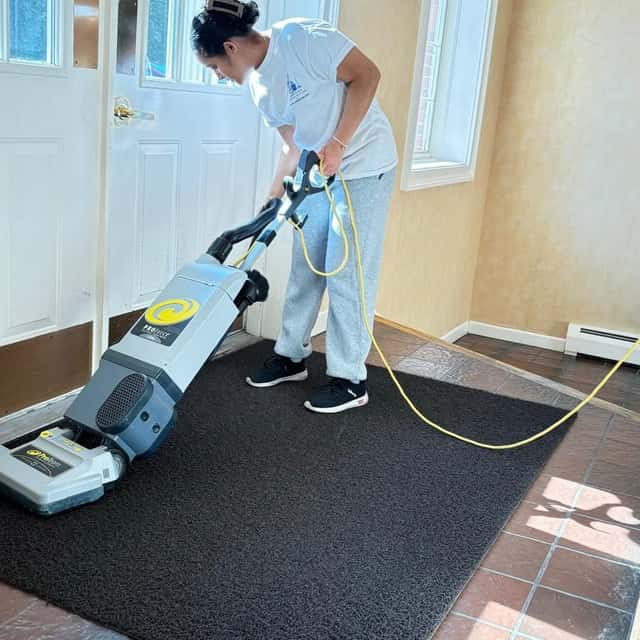 Vacuuming an entry mat by a bright doorway — MARTS-R.P Cleaning Solutions LLC